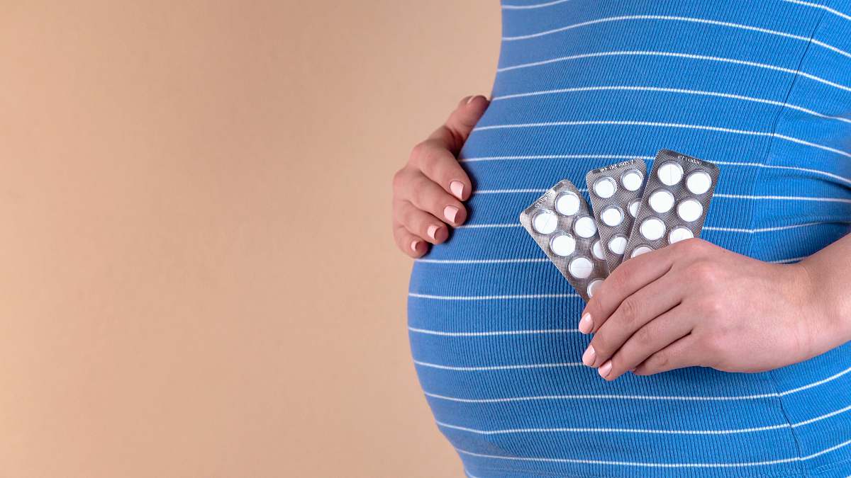 medicine pregnant woman in blue dress holding blister pack medical care
