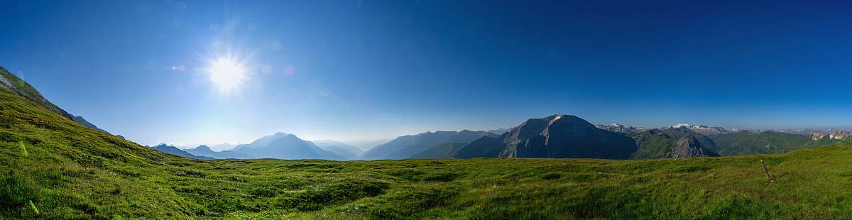 outdoors green grass field near mountain under blue sky during daytime scenery