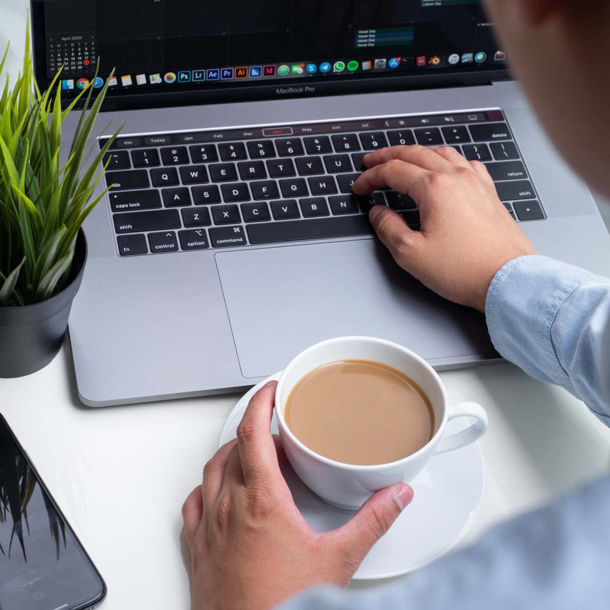 aesthetic person holding white ceramic mug on macbook pro coffee
