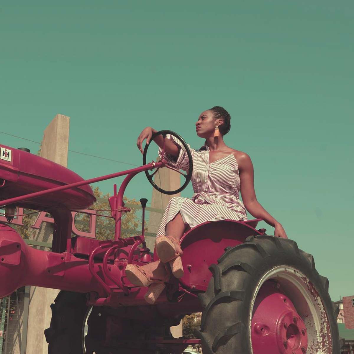  woman in white tank top riding red tractor during daytime 