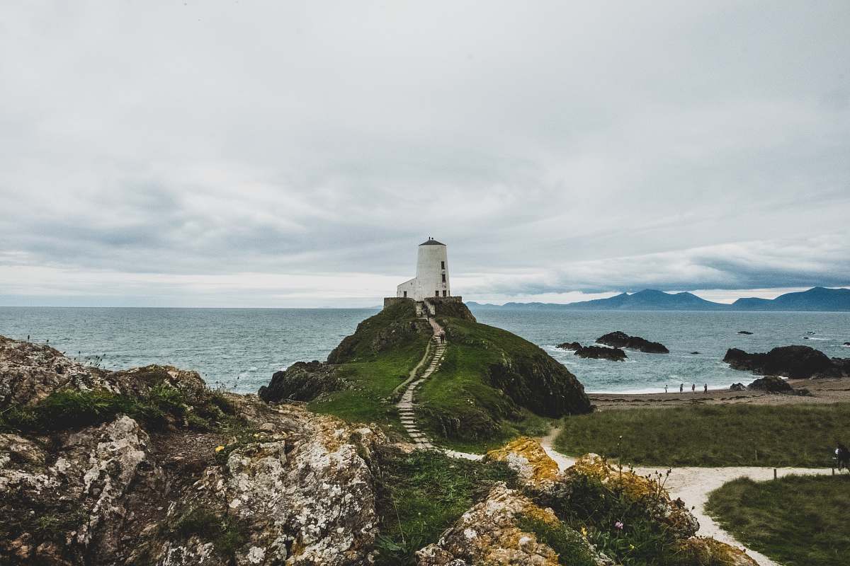 ocean white lighthouse on green grass field near body of water during daytime sea