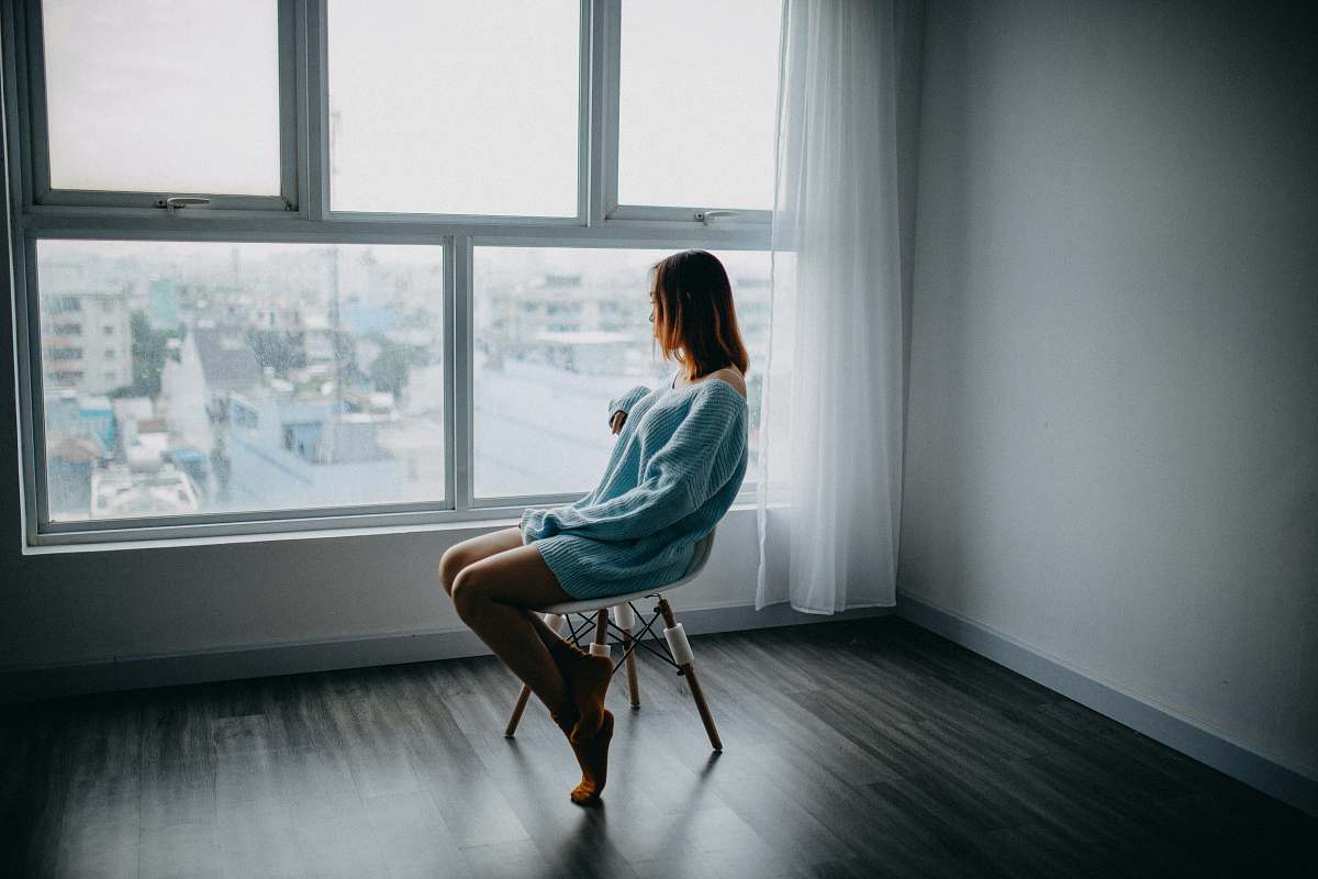 unhappy woman sitting on brown chair beside glass window chair
