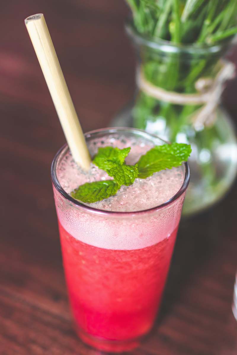 bali shallow focus photography of clear drinking glass with pink liquid on brown wooden surface indonesia