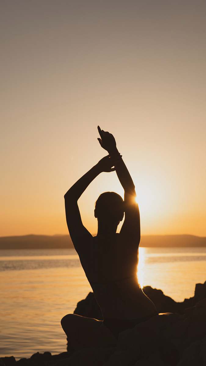 yoga silhouette of man raising his hands during sunset blessed
