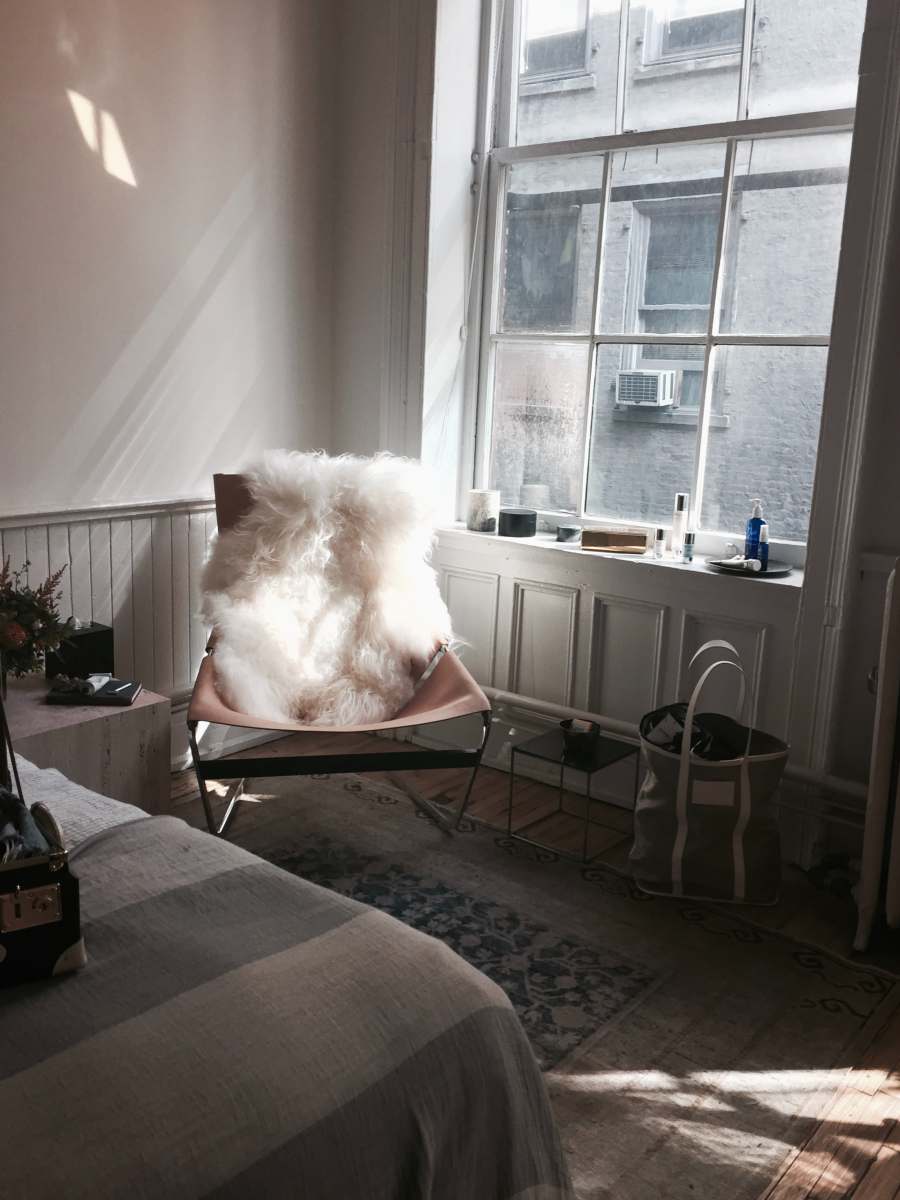 nyc white fur chair cover on brown chair beside glass window the apartment by the line