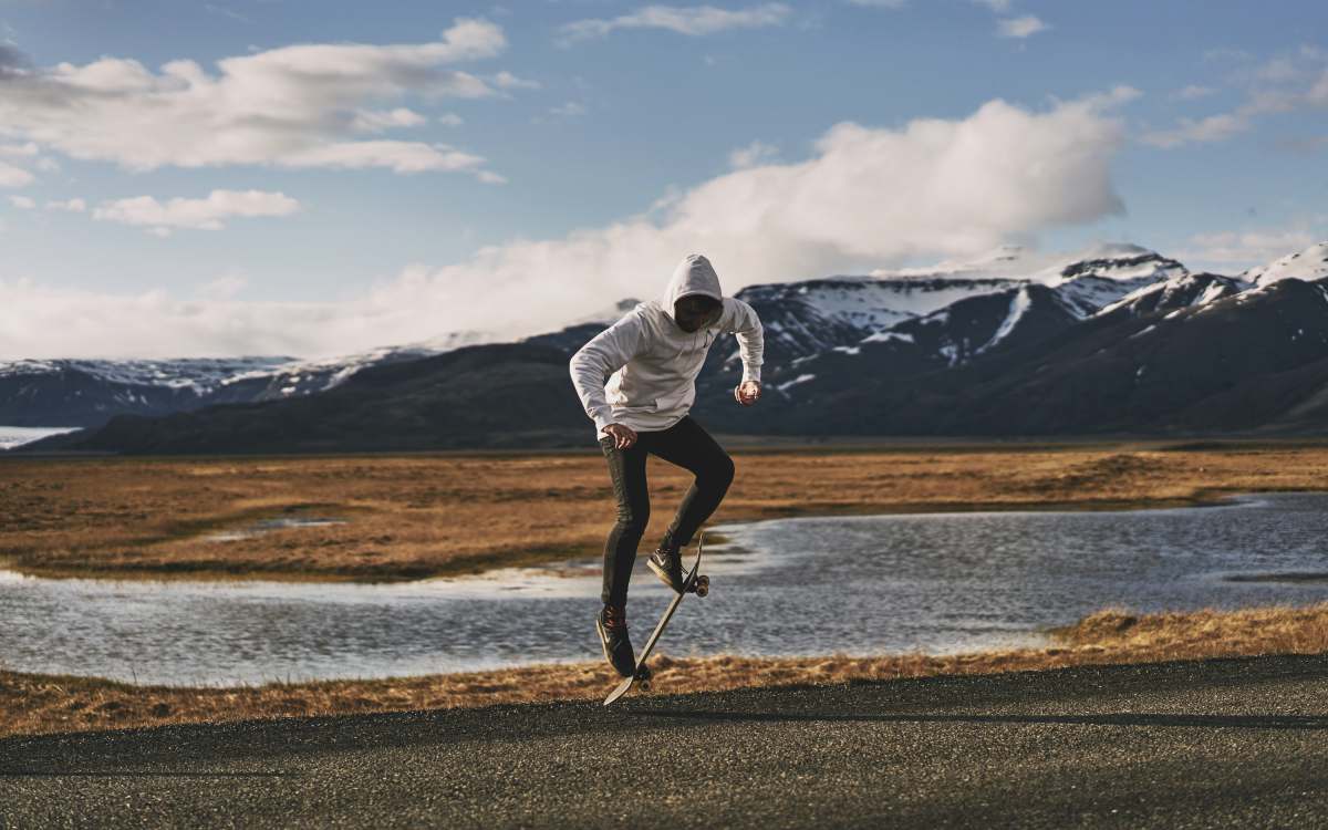 water man doing tricks on skateboard near body of water road