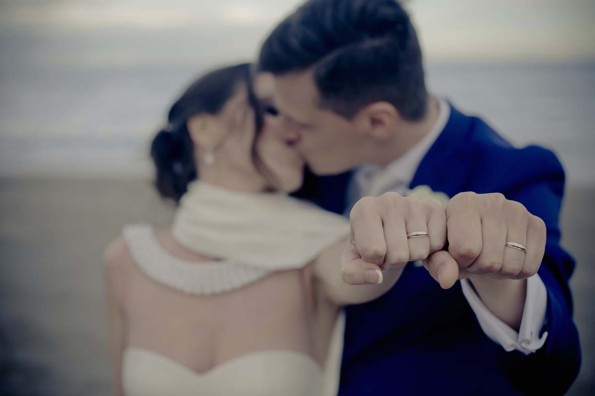 rings couple kissing while showing off their wedding rings man