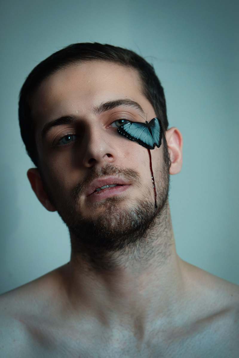 This striking portrait features a human man with a prominent black mustache and beard, complemented by a distinctive broken eye that adds an element of intrigue and depth to his expression. Ideal for creative projects, this image can be used in advertising campaigns, character studies, or storytelling visuals that explore themes of resilience and individuality. Perfect for photographers, artists, and content creators looking to convey strong emotions and unique narratives.
