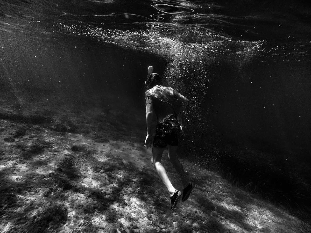 ocean grayscale photography of man swimming underwater mediterranean sea