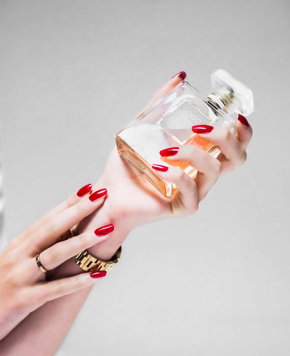 fragrance person holding clear glass bottle perfume