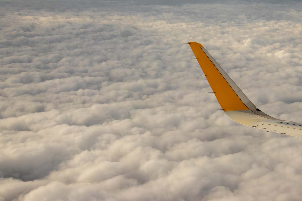 airplane yellow airplane tail on white clouds flying
