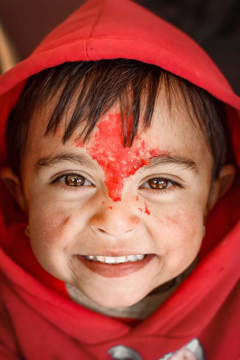 nepal woman in red hijab with white powder on her face smiling