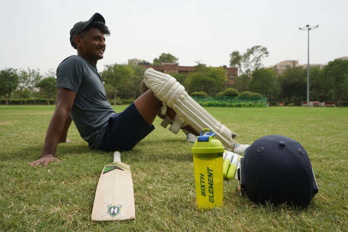 sports man in gray t-shirt and black cap holding white plastic bottle cricket