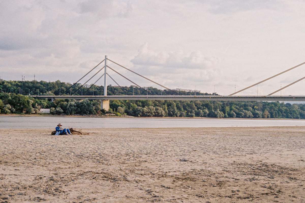  people on beach near bridge under white sky during daytime 