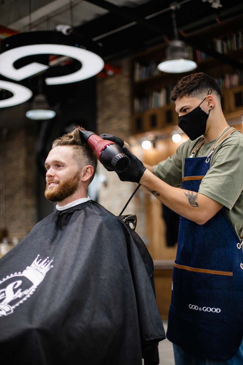 hairdresser man in green and black crew neck t-shirt holding black dslr camera 