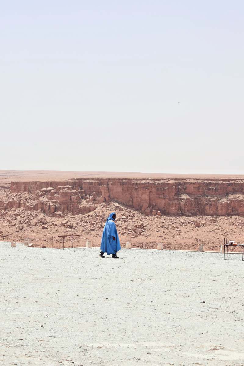  woman in blue dress walking on white sand during daytime 