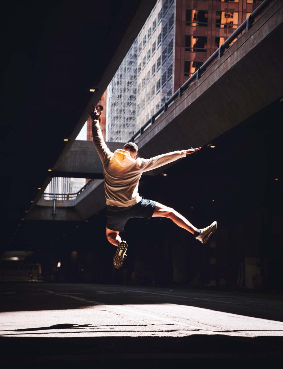  man in white and black stripe shirt and black shorts jumping on mid air 