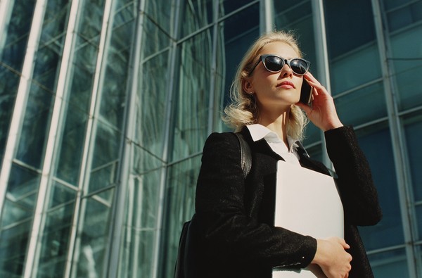 blonde business woman holding laptop and talki