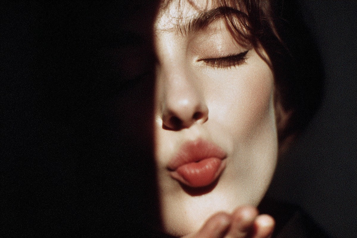 In this intimate image, a woman blows a kiss with her eyes gently closed, exuding a sense of warmth and affection. This visual captures a moment of vulnerability and connection that can be used in campaigns focused on love, friendship, or self-expression. Ideal for social media posts, advertisements, or personal blogs, it resonates with themes of intimacy and emotion.