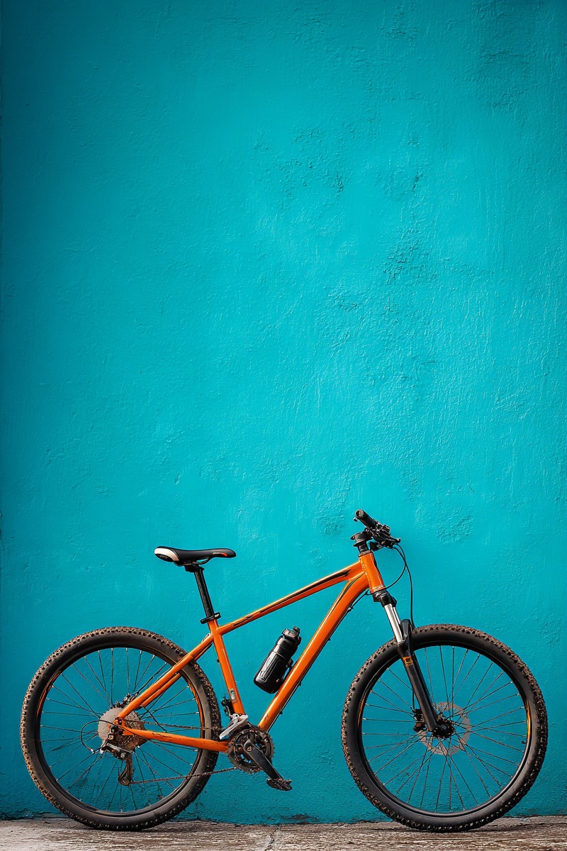 orange mountain bike leaning cyan wall adventur