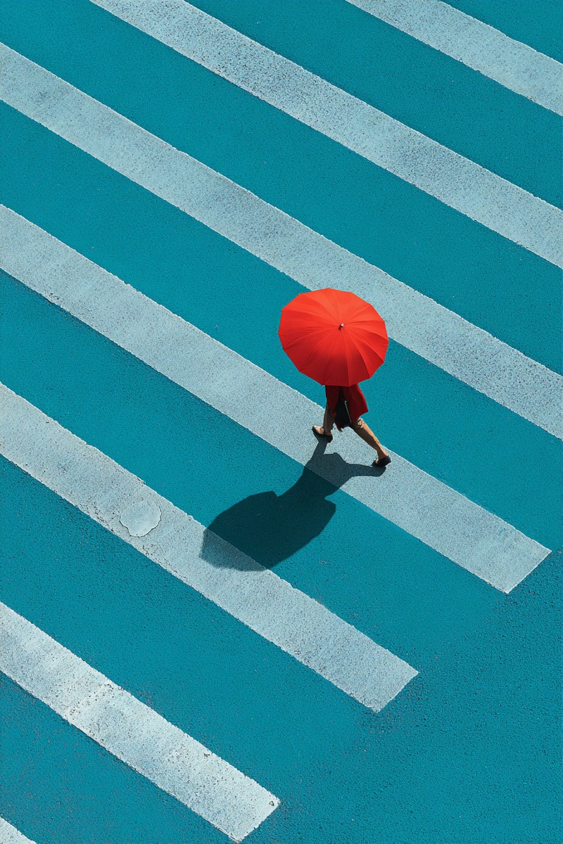 person walking with red umbrella across cyan cro