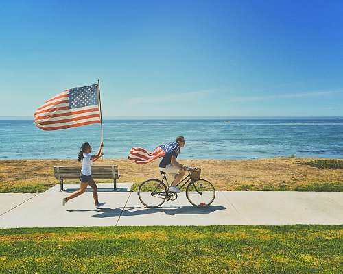 bicycle man riding bike and woman running holding flag of USA san diego