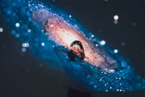 female woman covering her face using right hand with galaxy background illuminated