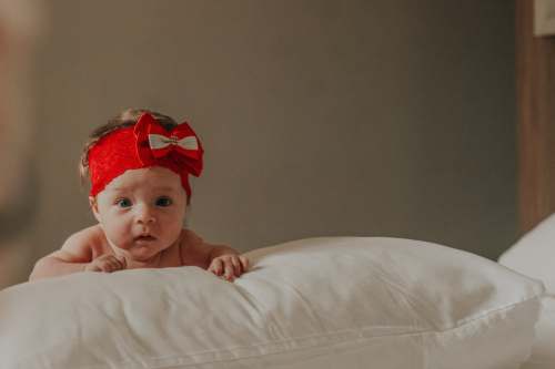 clothing baby in red headband lying on bed girl