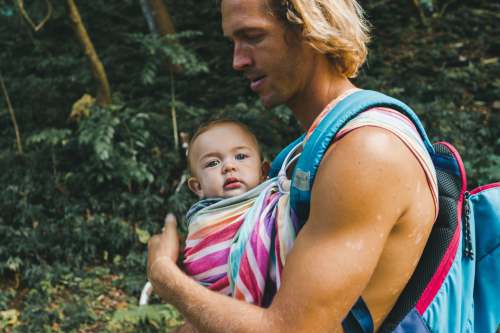 family woman in blue tank top carrying baby in pink and white stripe shirt love