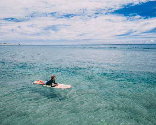blue woman lying on surfboard ocean