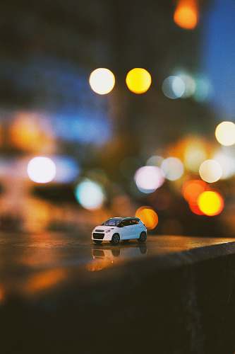 vehicle bokeh photography of white car miniature toy