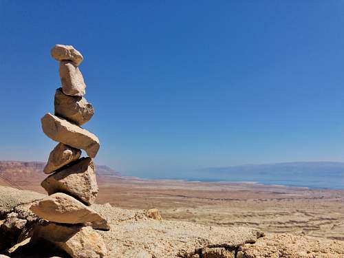 israel brown rocks on brown sand under blue sky during daytime masada