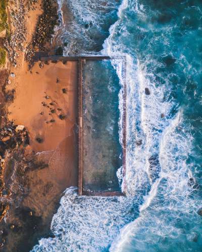 wallpaper aerial photography of sea hitting sand at daytime android wallpapers