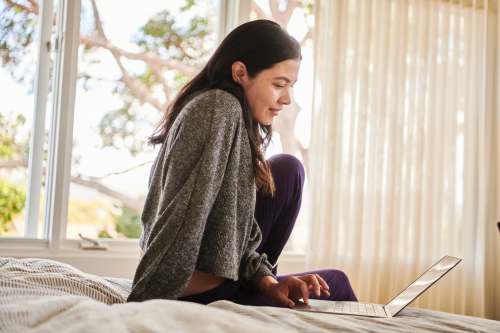 people A woman on a bed working on signing a contract with Docusign electronics