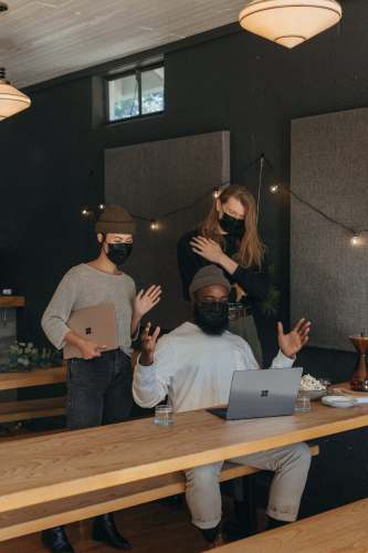 working Three coworkers wearing masks talking with someone on video chat in an office microsoft