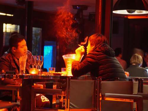china man in black long sleeve shirt smoking nightlife