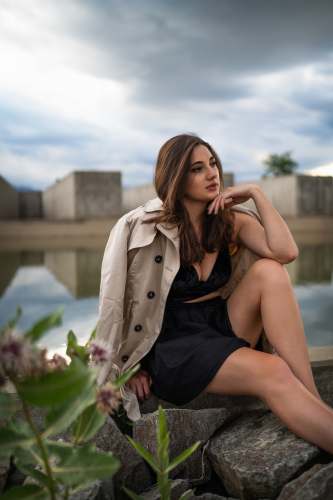  woman in black dress sitting on concrete bench during daytime 