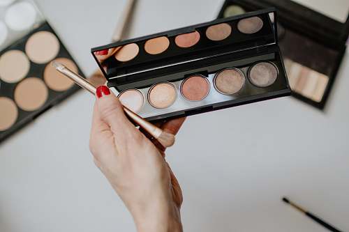 palette person holding makeup brush with makeup palette cosmetics