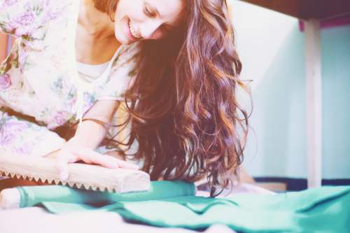 textile woman smiles while holding brown wooden frame happy worker