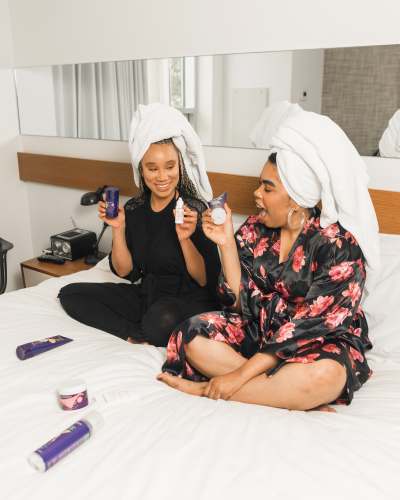  two women sitting on bed holding soft-tube 