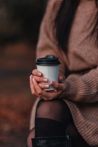  woman in brown sweater holding white disposable cup 