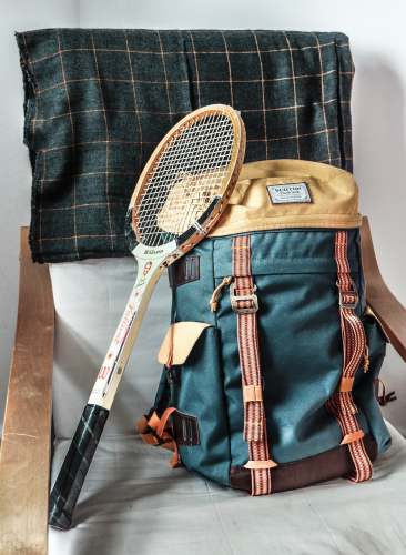  vintage brown tennis racket and green hiking backpack 