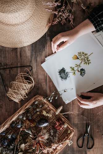 hat person holding white and green floral paper 