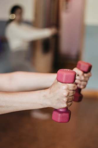  person holding pink and white dumbbells 